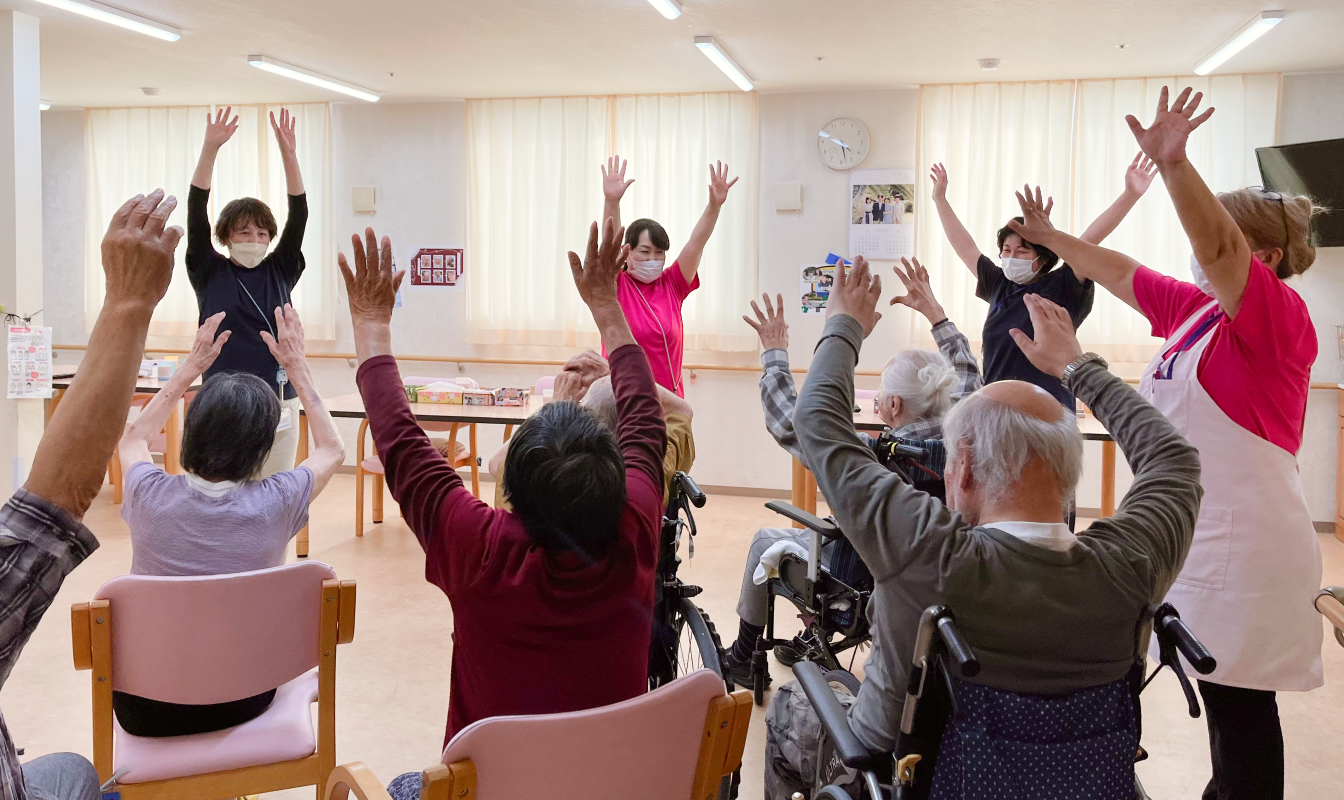 職員の方々と一緒に手を上げて運動している参加者の様子